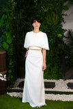 Ensemble de mariée minimaliste composé d’une jupe, d’un top et d’un petit cape-poncho, disponible à acheter en ligne
