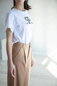 T-shirt blanc avec logo imprimé en coton vue de profil avec pantalon beige